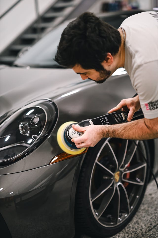 atelier-carrosserie Carrossier nettoyant et polissant une voiture grise